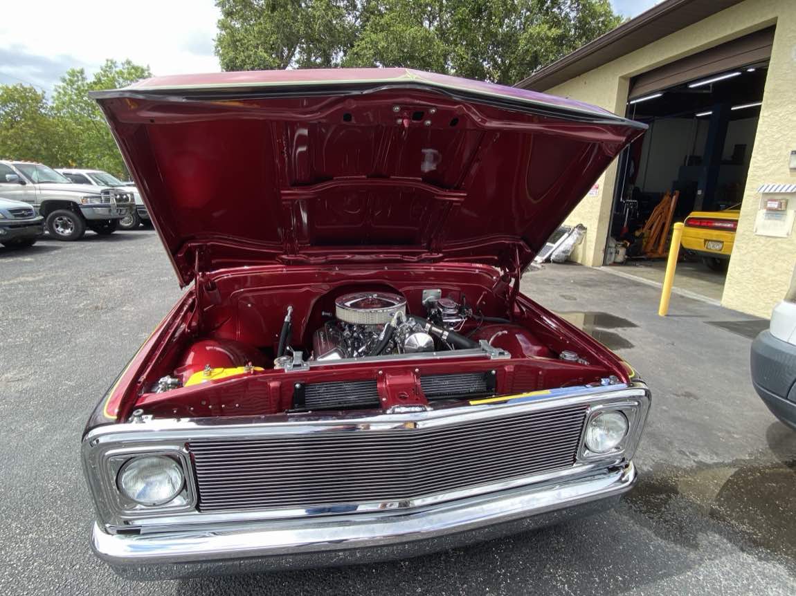 A restored classic Chevy pickup with a rebuilt engine, hood open, outside Harvey's Auto Repair in Cocoa